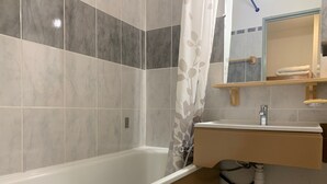 Une salle de bain avec une baignoire, un lavabo et un miroir.