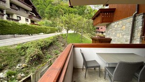 Un balcón con vistas a una carretera y vegetación, un muro de piedra y una estructura de madera.