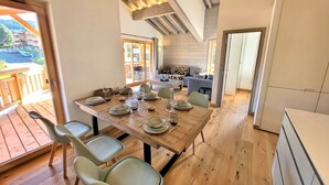 A dining area with a wooden table set for four, a sofa, and a kitchen in the background. - Bright apartment 3BR, large balcony (Les Gets)