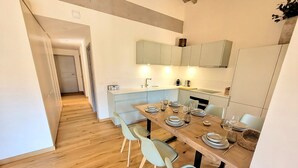 A modern kitchen with a dining area, wooden flooring, light-colored cabinets, and a central island. - Bright apartment 3BR, large balcony (Les Gets)