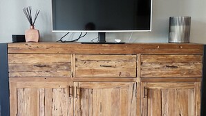 A wooden cabinet with a flat-screen TV on top, a vase with reeds, and a decorative vase. - Comfortable renovated studio in green residence in Chamonix (Chamonix-Mont-Blanc)
