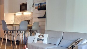 A modern living room with a grey sofa, wooden coffee table, and a dining area with chairs and a table. - Comfortable renovated studio in green residence in Chamonix (Chamonix-Mont-Blanc)