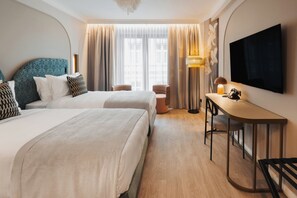 A hotel room with two beds, a desk, a chair, a TV, and a large window with curtains. - Hotel Indigo Krakow Wawel Castle by IHG (Kraków)