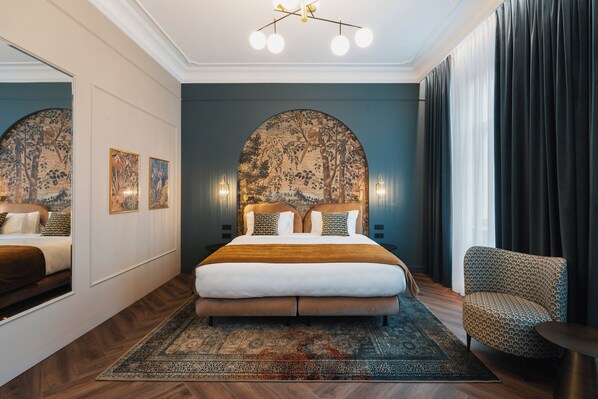 A bedroom with a large bed, a headboard with a nature-themed design, a patterned armchair, and a large mirror. - Hotel Indigo Krakow Wawel Castle by IHG (Kraków)