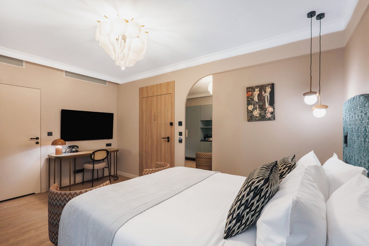 Habitación de hotel con cama, escritorio, silla y televisor.