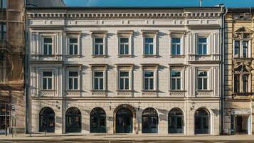 Un bâtiment historique à la façade symétrique, doté de nombreuses fenêtres et de portes en arc de cercle.