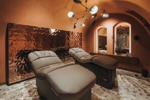 A spa room with two massage chairs, a large abstract wall, a mirror, and a ceiling light fixture. - Hotel Indigo Krakow Wawel Castle by IHG (Kraków)