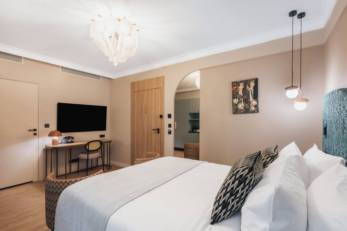 Habitación de hotel con cama, escritorio, silla y televisor.