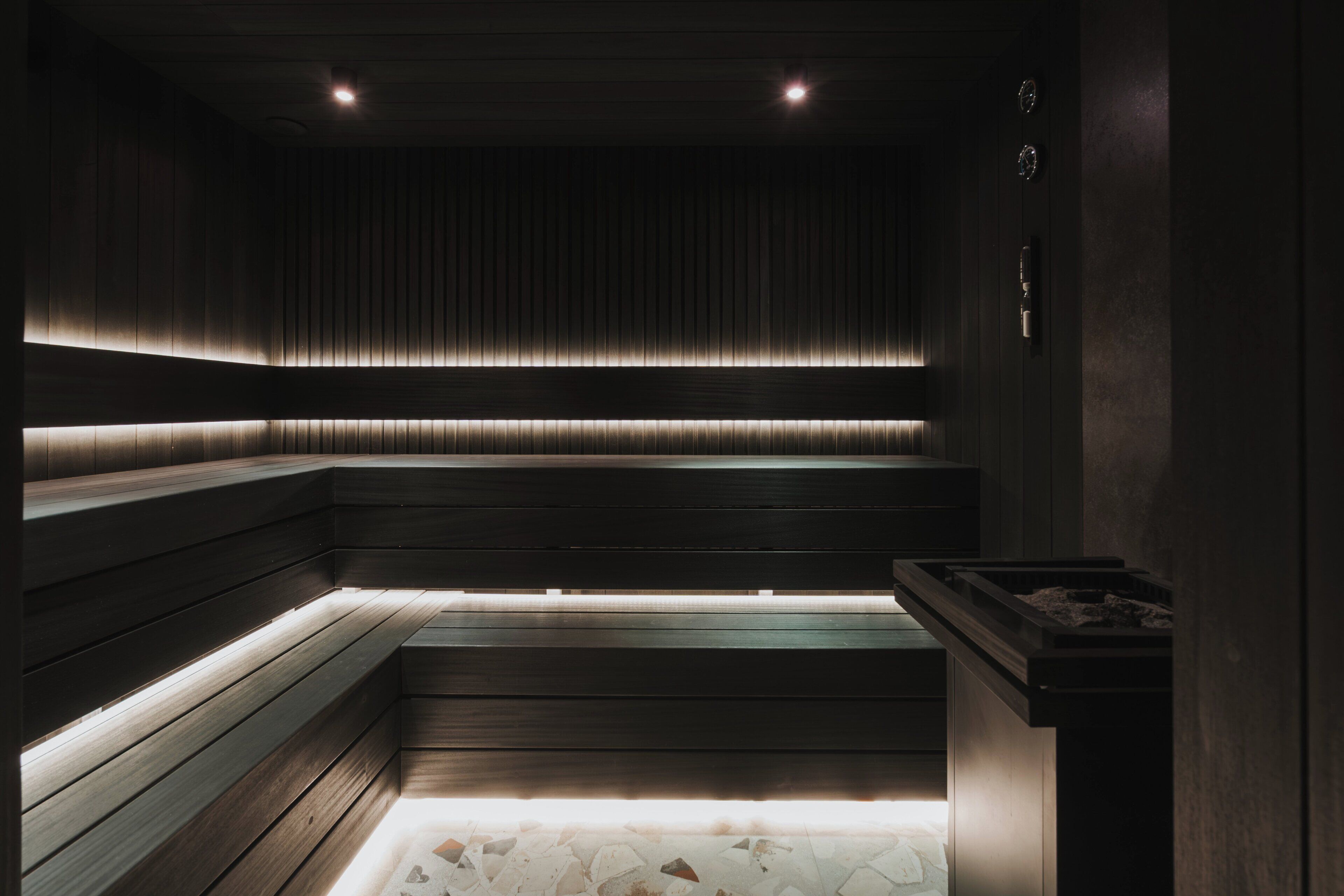 A dimly lit sauna with wooden benches and a tiled floor.