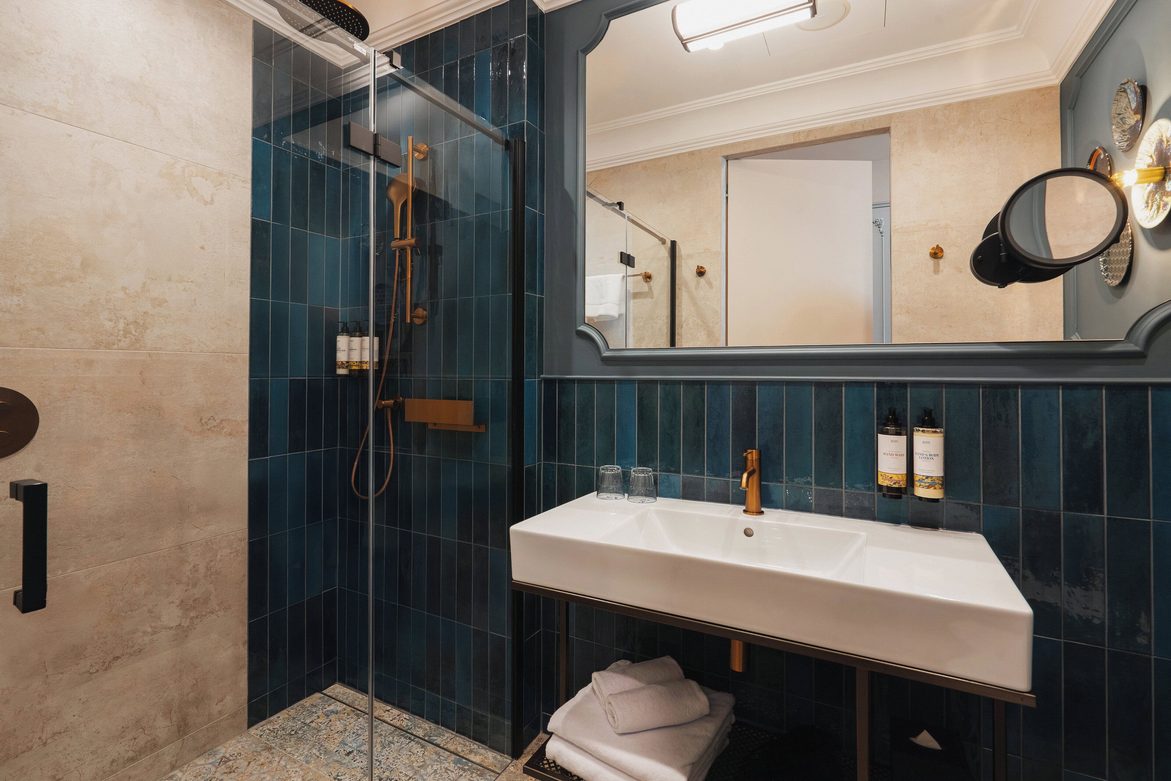 Un bany modern amb dutxa de vidre, un lavabo blanc i un mirall gran.