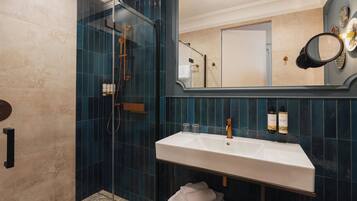 Un bany modern amb dutxa de vidre, un lavabo blanc i un mirall gran.
