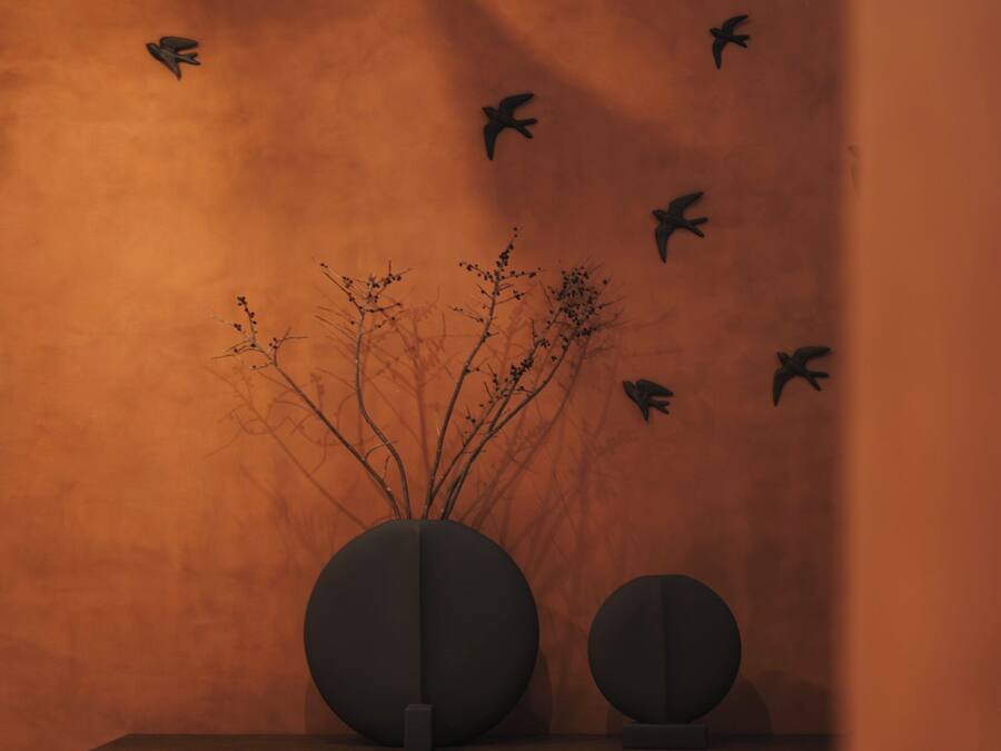 A room with a wooden cabinet, a vase with branches, and a tiled floor.