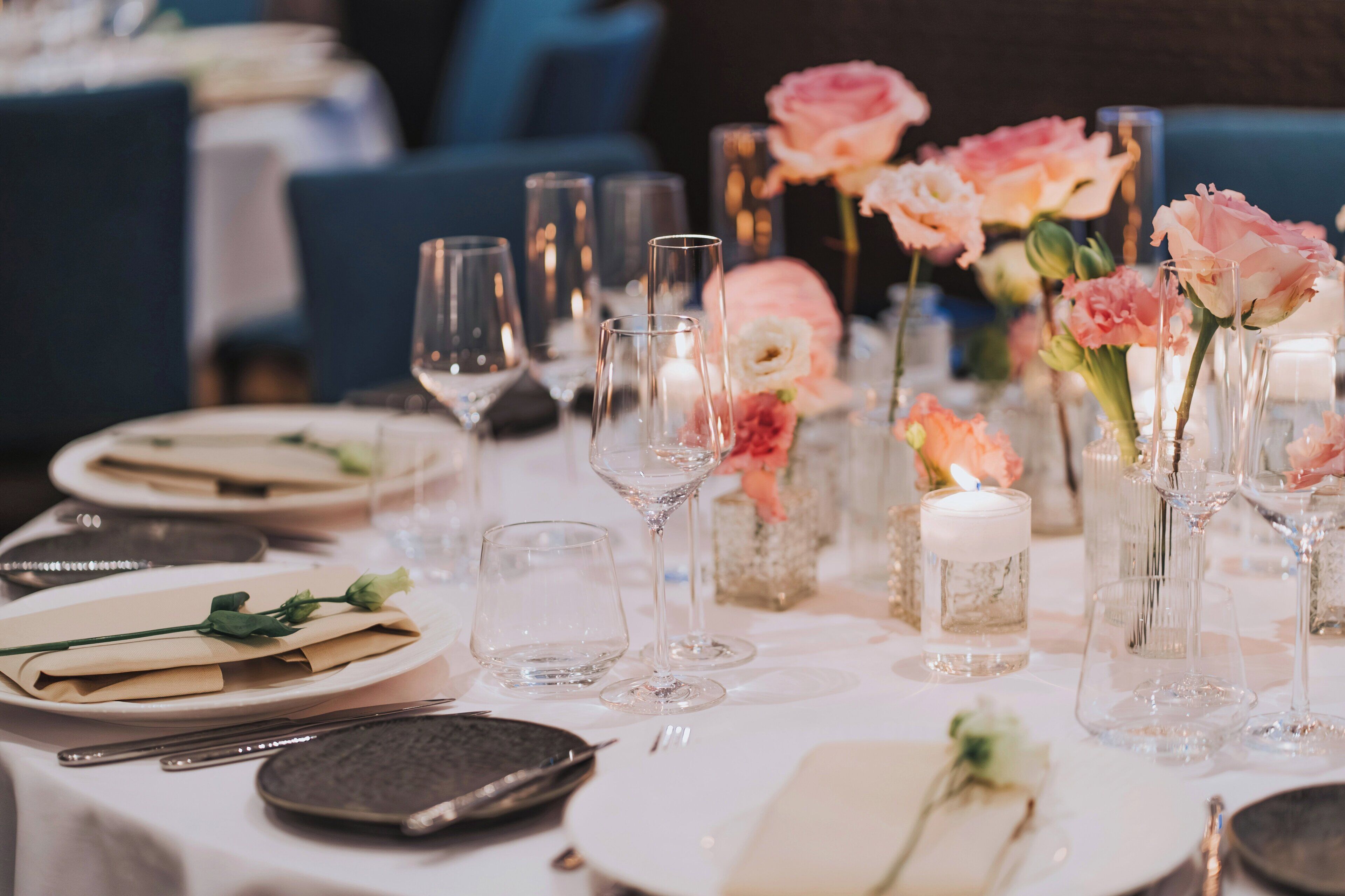 Une table dressée avec des assiettes, des couverts, des verres et des vases remplis de fleurs.