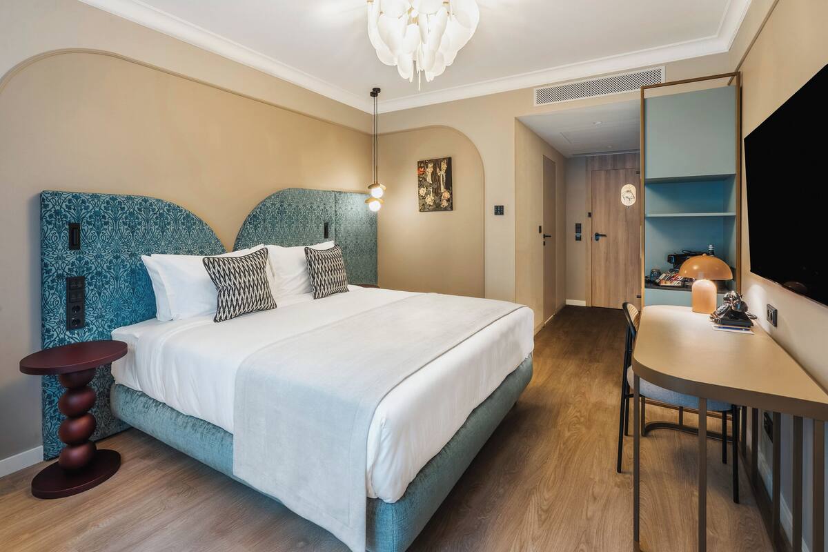 Un dormitorio moderno con una cama grande, una mesita de noche, un escritorio y una silla.