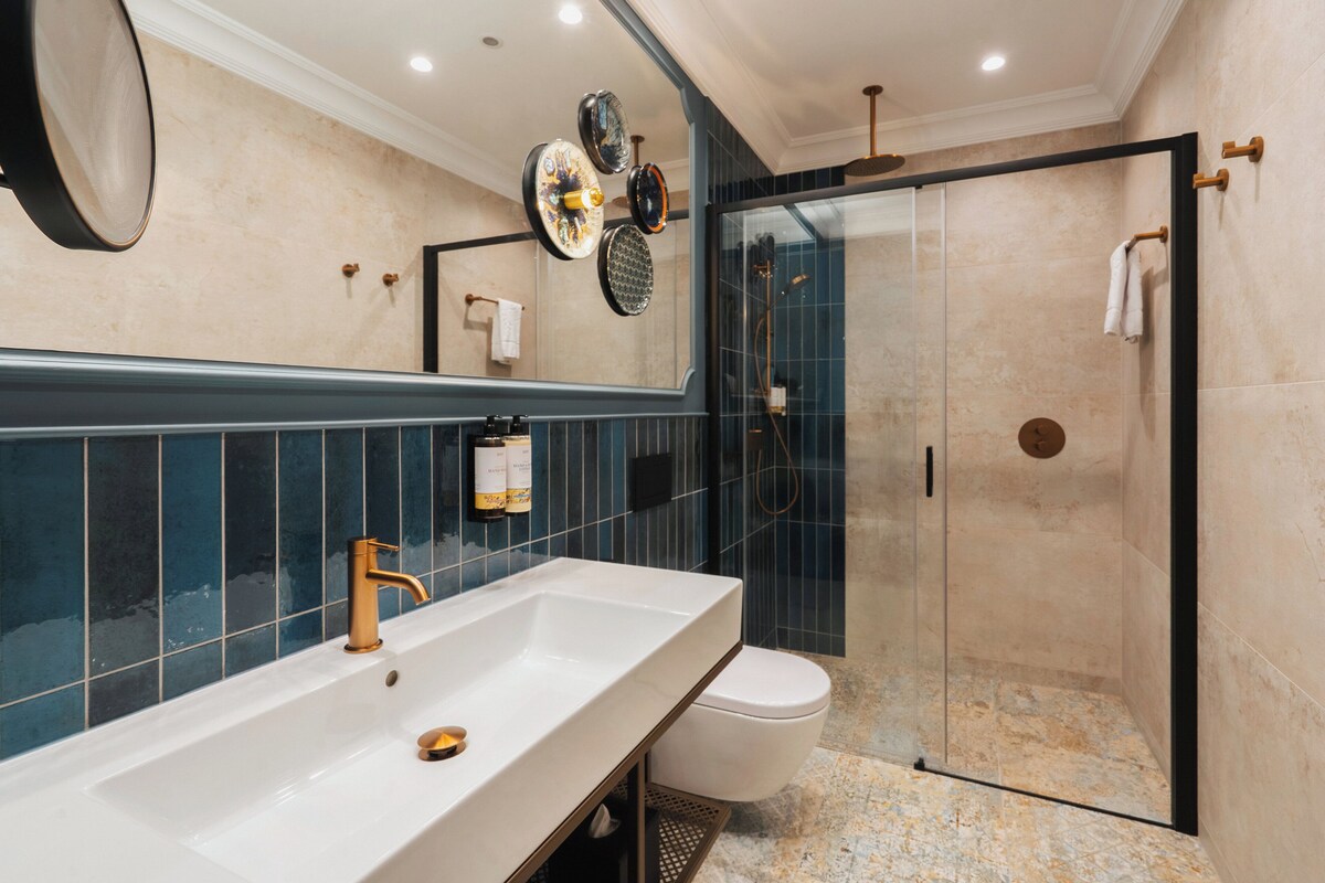 Un baño moderno con un lavamanos grande, un inodoro y una ducha con cerramiento de vidrio.