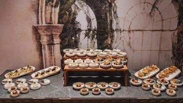 A buffet with various dishes arranged on a table against a wall with a decorative arch.