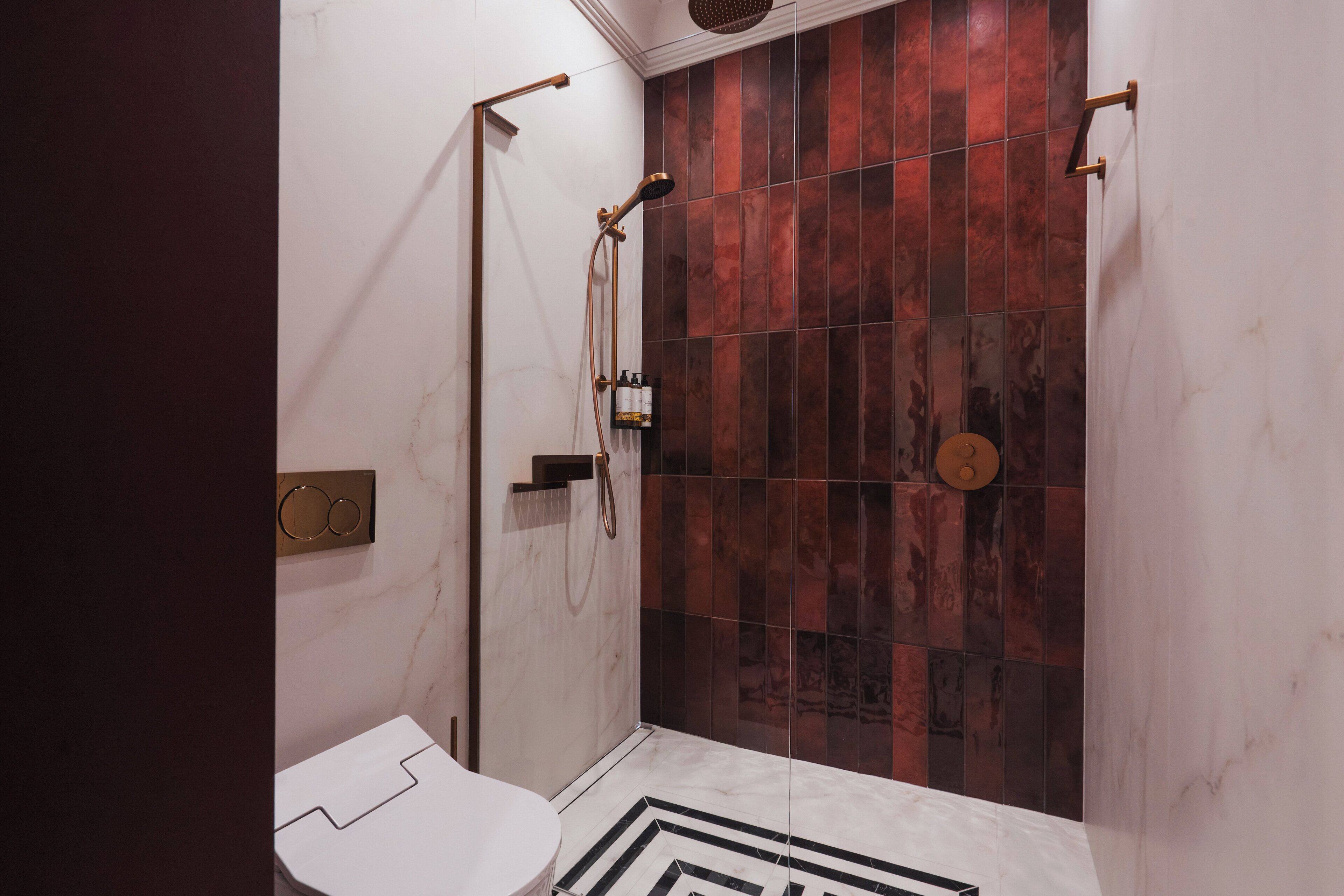 Een moderne badkamer met een douche, toilet en een marmeren vloer.
