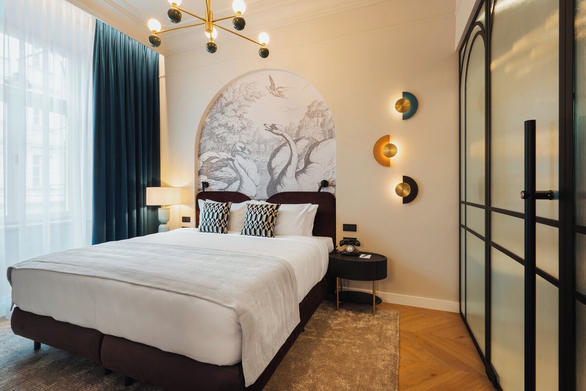 Habitación de hotel con una cama grande, una mesita de noche, una lámpara de pared y un adorno mural.