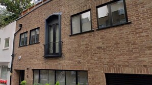 A brick building with a large window, a small balcony, and a garage door. - Central London Charm One Bedroom Apartment (London)