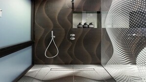 A modern bathroom with a unique wood panel design, a shower with a handheld showerhead, and a patterned floor. - Central London Charm One Bedroom Apartment (London)