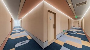 A hotel corridor with a check-in desk, a reception area, and a door with a sign.