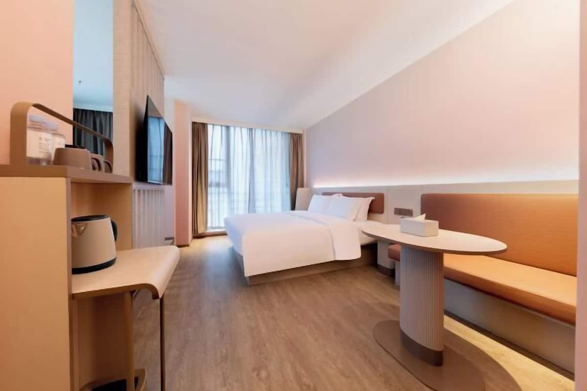 Une chambre d’hôtel moderne équipée d’un lit, d’une table de chevet, d’un petit coin salon et d’un téléviseur.