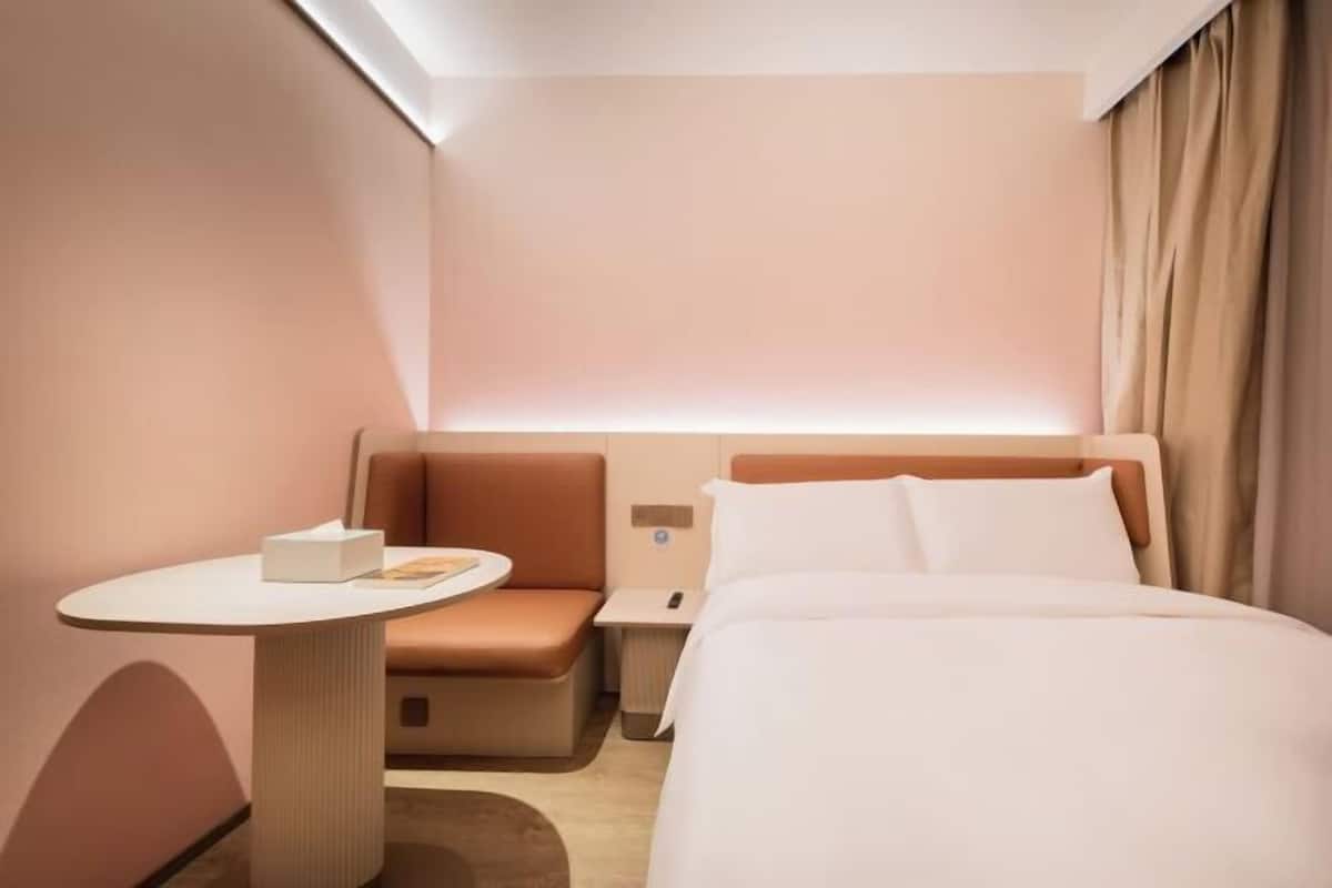 Une chambre d’hôtel moderne, équipée d’un lit, d’une petite table, d’un canapé et d’une table de chevet.