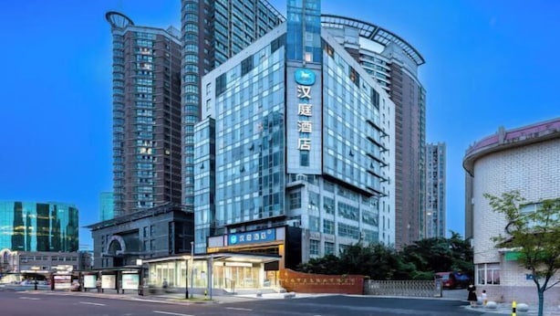 A modern hotel with a curved facade, large windows, and a prominent sign.