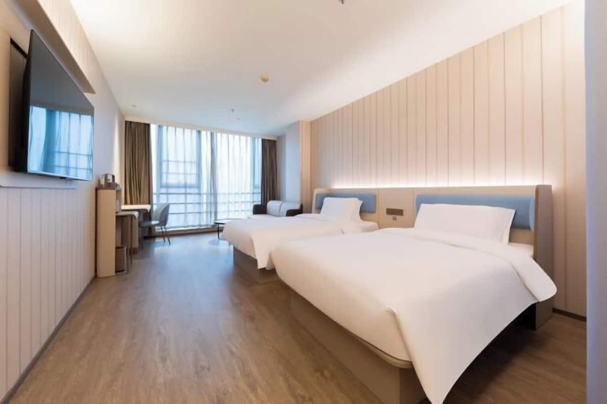 Une chambre d’hôtel avec deux lits, une télévision, un bureau et une chaise.
