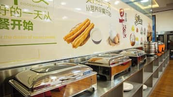 A buffet setup with multiple food service stations, a wall with promotional text, and a clean, organized layout.