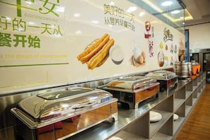 A buffet setup with multiple food service stations, a wall with promotional text, and a clean, organized layout.
