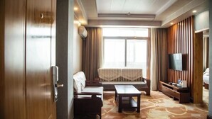 A hotel room with a sofa, a small table, a TV, and a large window with curtains. - Quzhou Ying Hotel (Quzhou)