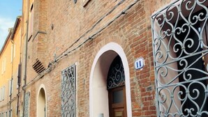 Edifici de maó amb portals arquejats i reixes metàl·liques decoratives.