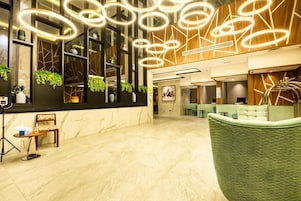 A modern lobby with a marble floor, a reception desk, and a green seating area.