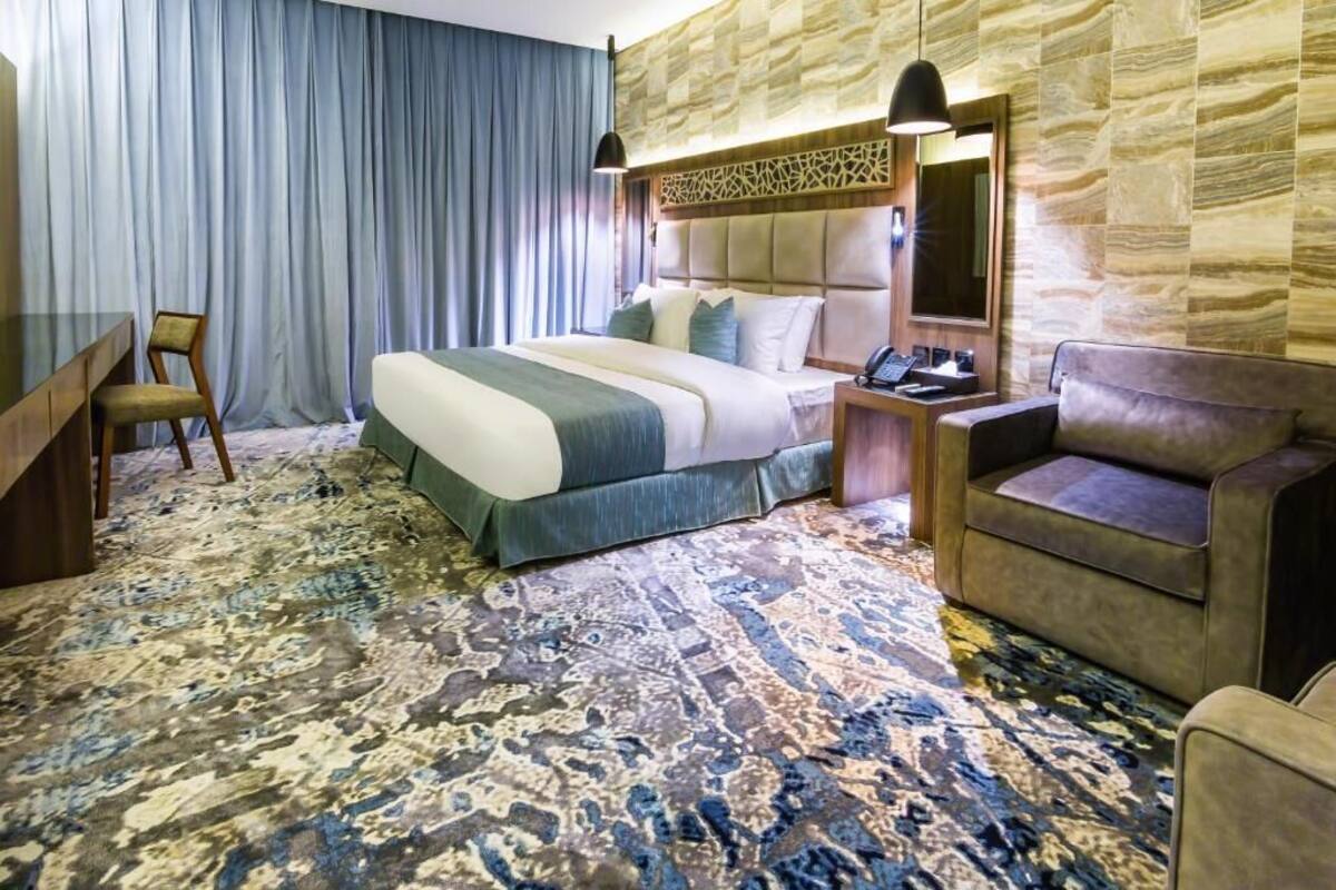 Ein Hotelzimmer mit einem großen Bett, einem Schreibtisch, einem Sessel und einer Couch.