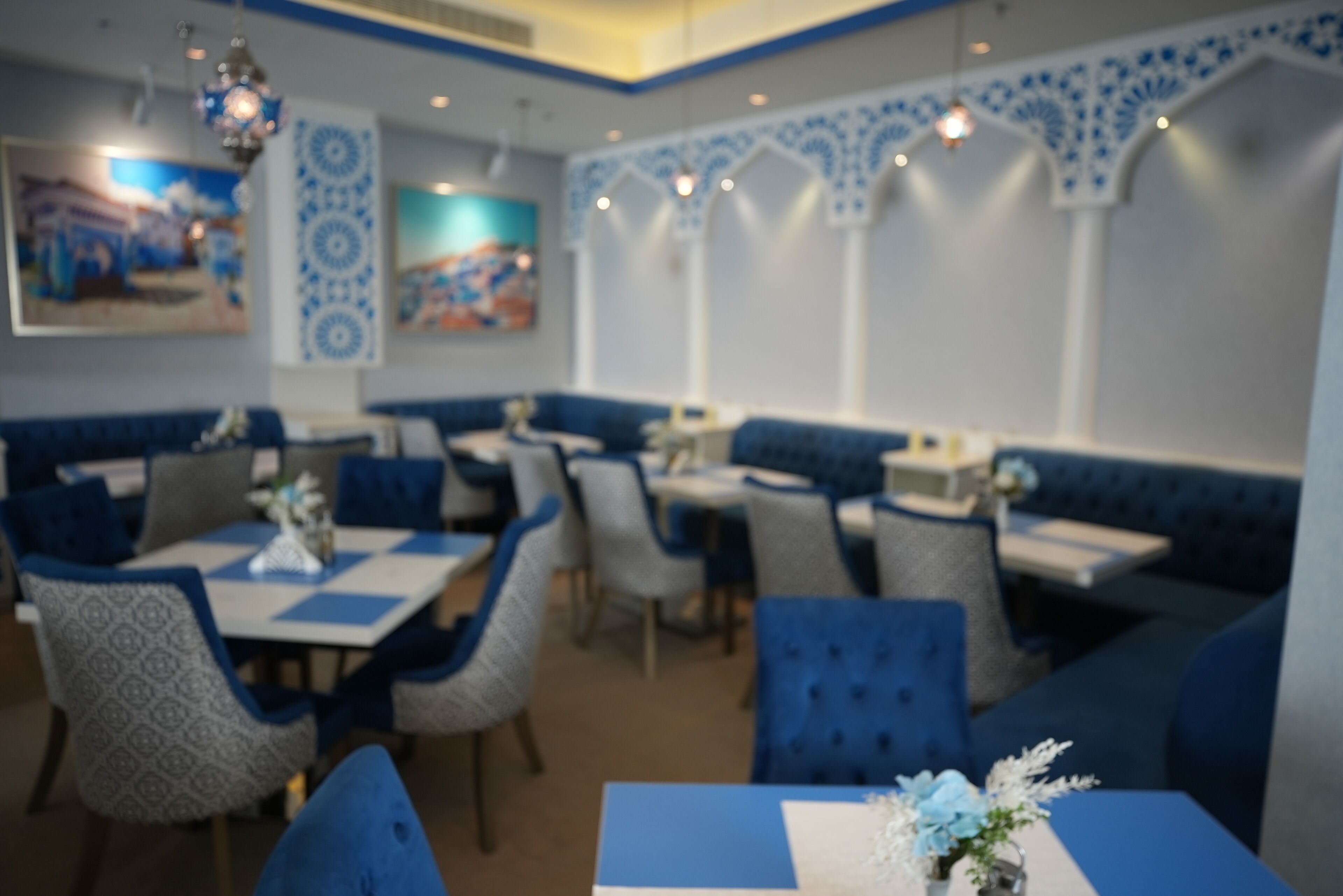 A restaurant with blue and white decor, featuring cushioned booths and tables.