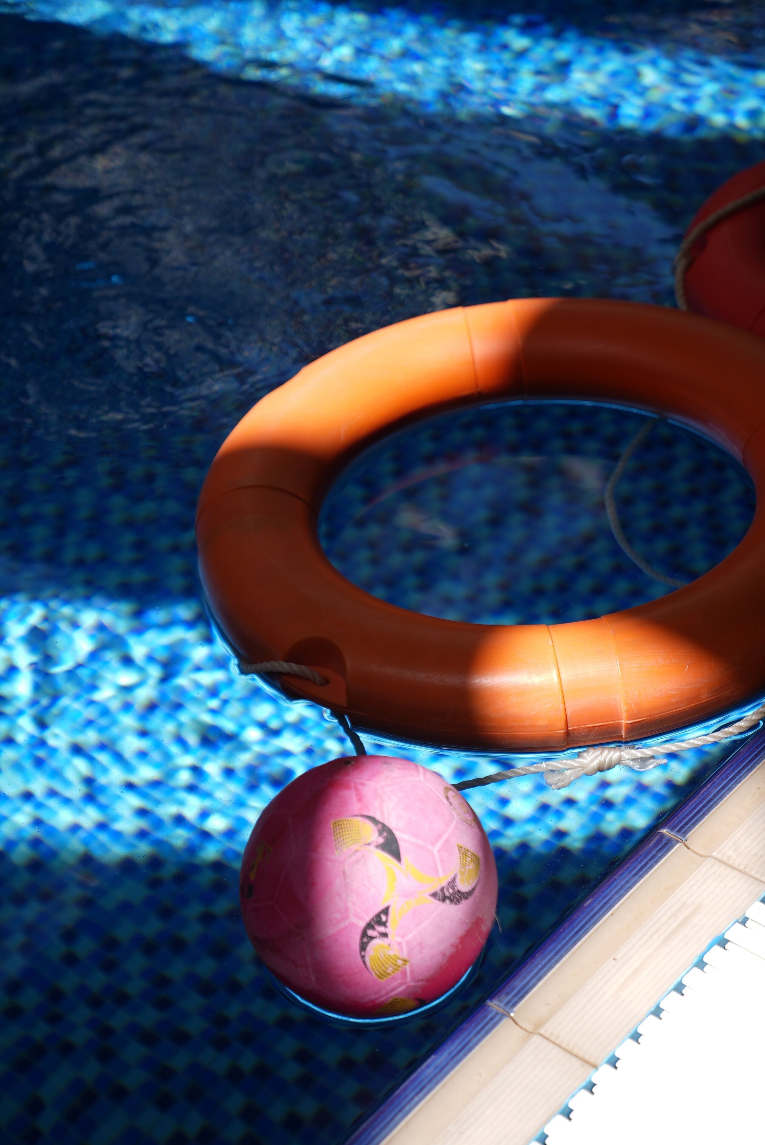 A pool with a blue tiled floor and a floating orange ring.