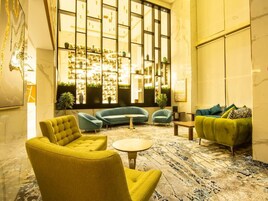 A spacious lobby with a large window, multiple seating areas, and a decorative wall.