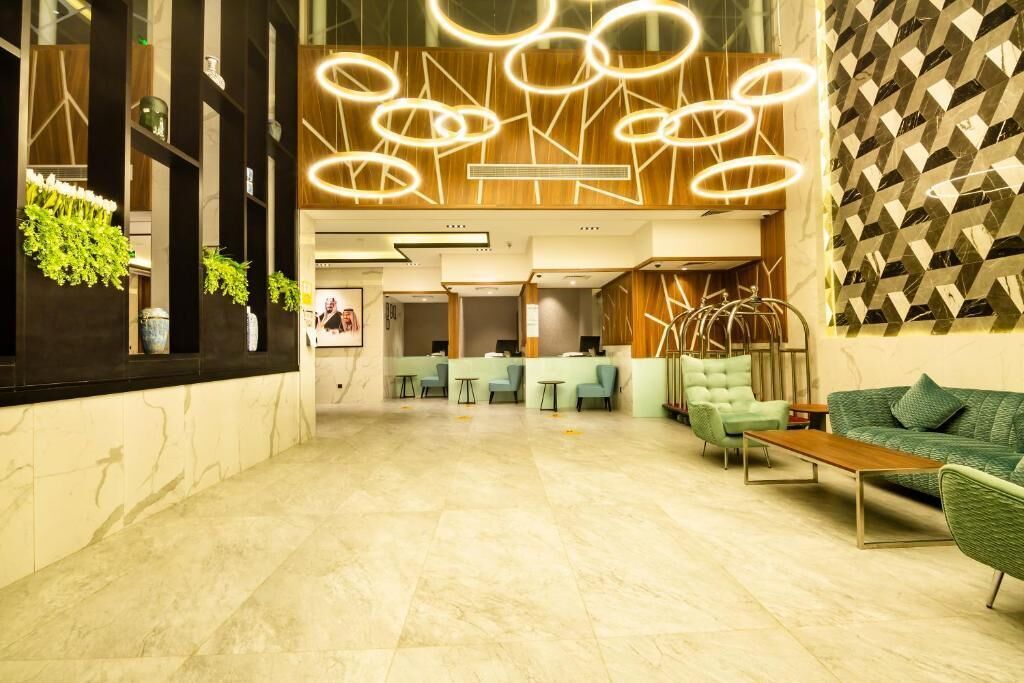 A modern lobby with a marble floor, green seating area, and a geometric patterned wall.