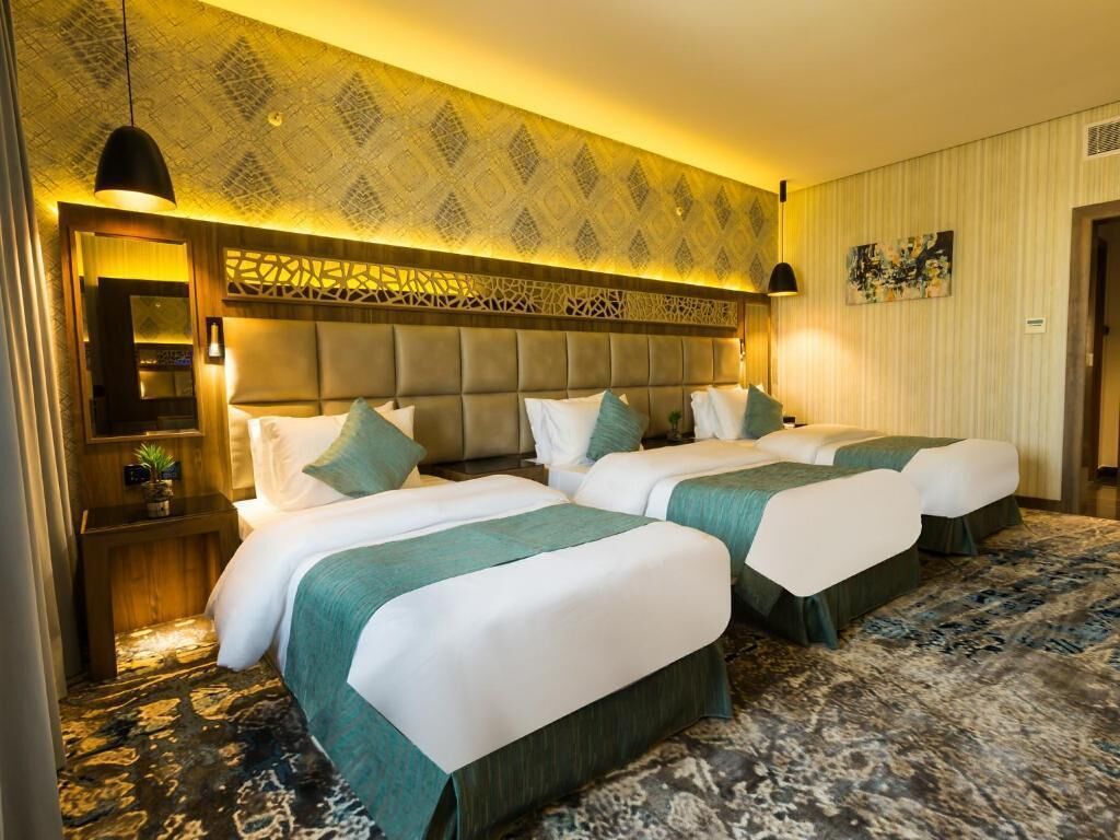 Habitación de hotel con dos camas, un papel tapiz estampado y un cabecero decorativo.