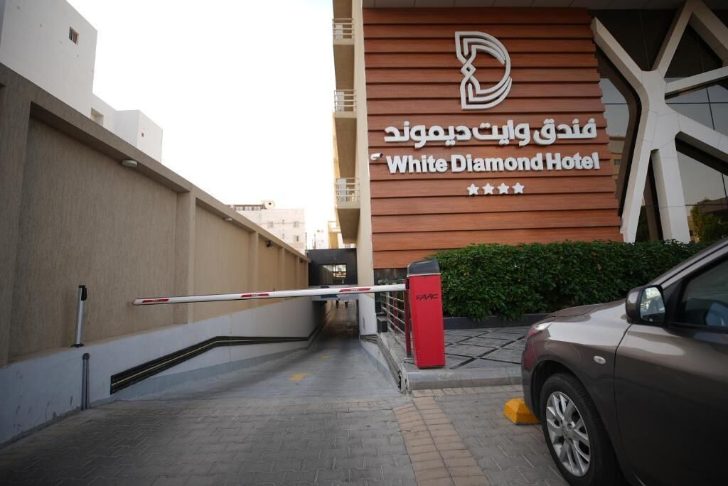 The entrance to the White Diamond Hotel with a modern design, a gated entrance, and a red security box.
