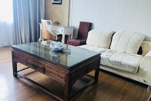 A room with a glass-top coffee table, a white sofa, and a red chair. - Junfu Hotel (Guangzhou Panyu Square Metro Station) (Guangzhou)