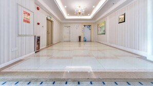 A spacious hallway with a tiled floor, white walls, and a chandelier. - Junfu Hotel (Guangzhou Panyu Square Metro Station) (Guangzhou)
