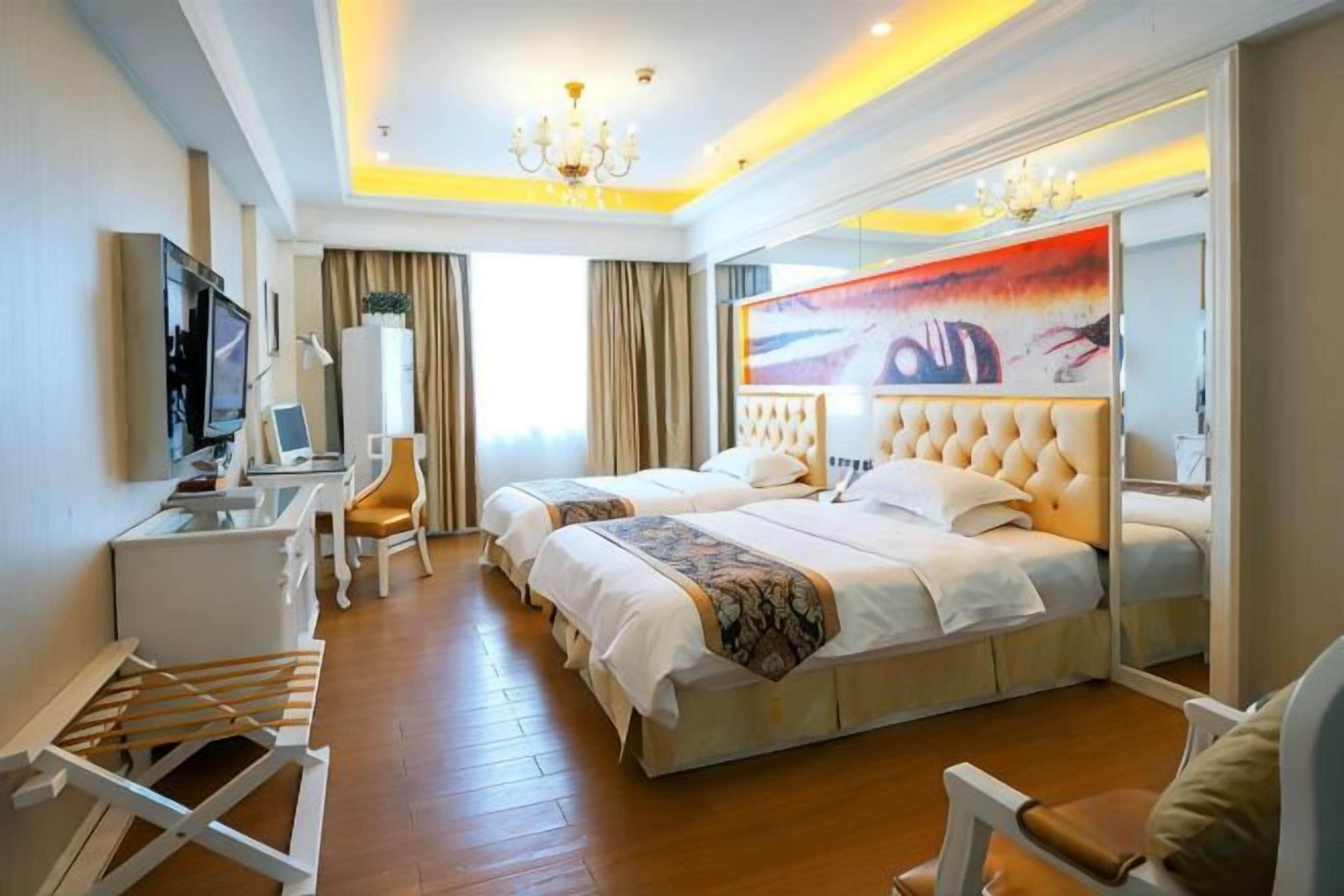 A hotel room with a large bed, a desk, a chair, and a television.