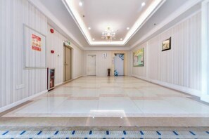 A hotel corridor with a chandelier, doors, and framed pictures on the walls. - Junfu Hotel (Guangzhou Panyu Square Metro Station) (Guangzhou)