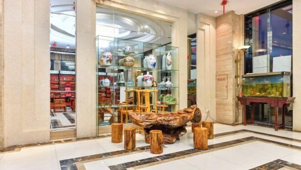 A modern interior with a glass display of pottery, wooden stools, and a fish tank. - Junfu Hotel (Guangzhou Panyu Square Metro Station) (Guangzhou)