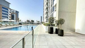 A rooftop pool area with a clear view of the city skyline, modern buildings, and a few potted plants. - Azizi Riviera 8 - Quiet Studio in Meydan (Meydan)