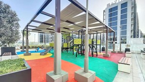 An outdoor play area with colorful flooring, exercise equipment, and a covered seating area. - Azizi Riviera 8 - Quiet Studio in Meydan (Meydan)