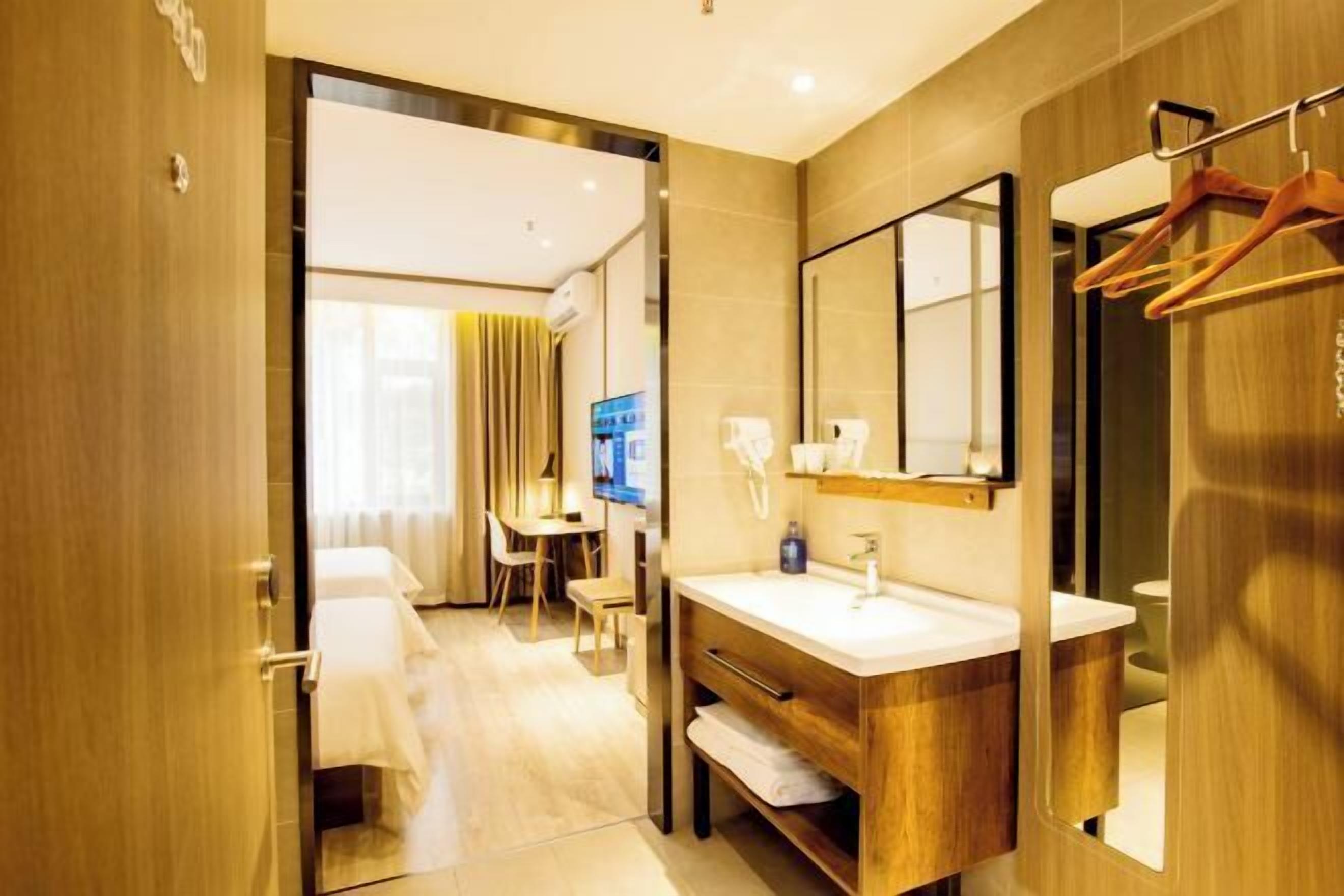 A hotel bathroom with a wooden vanity, a mirror, and a towel rack.