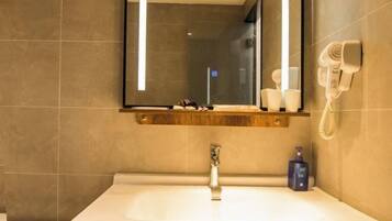 A bathroom with a large mirror, a sink, a hairdryer, and a towel rack.